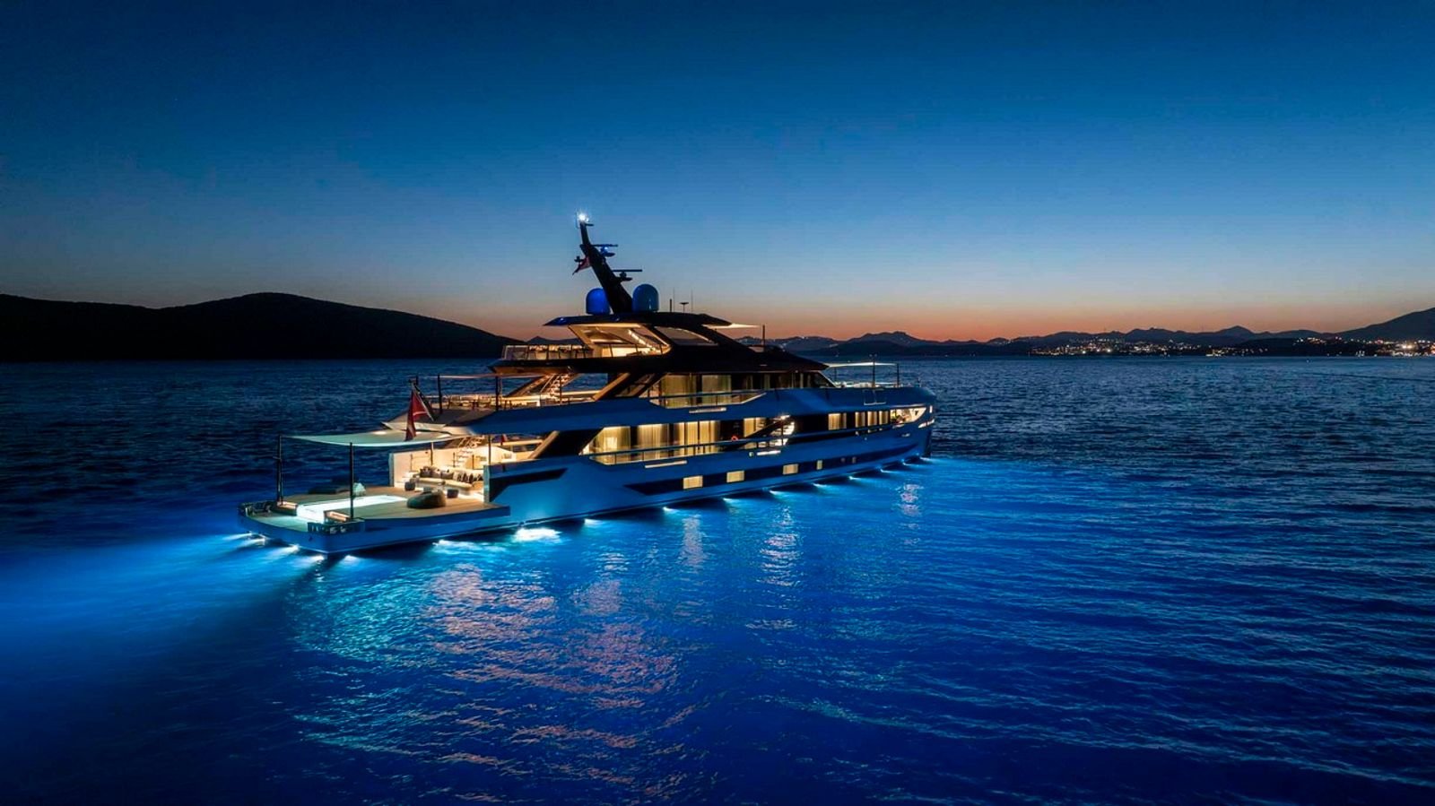 A 50m mega yacht at dusk with the beach club and hydraulic wings open
