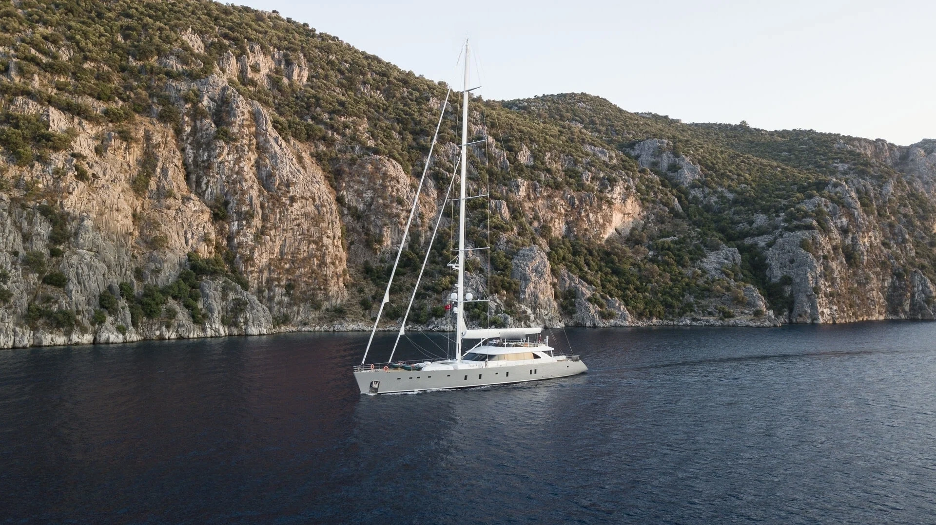 Aerial of a 50m motor sailer anchored below cliffs, Turkish Riviera — AA5019
