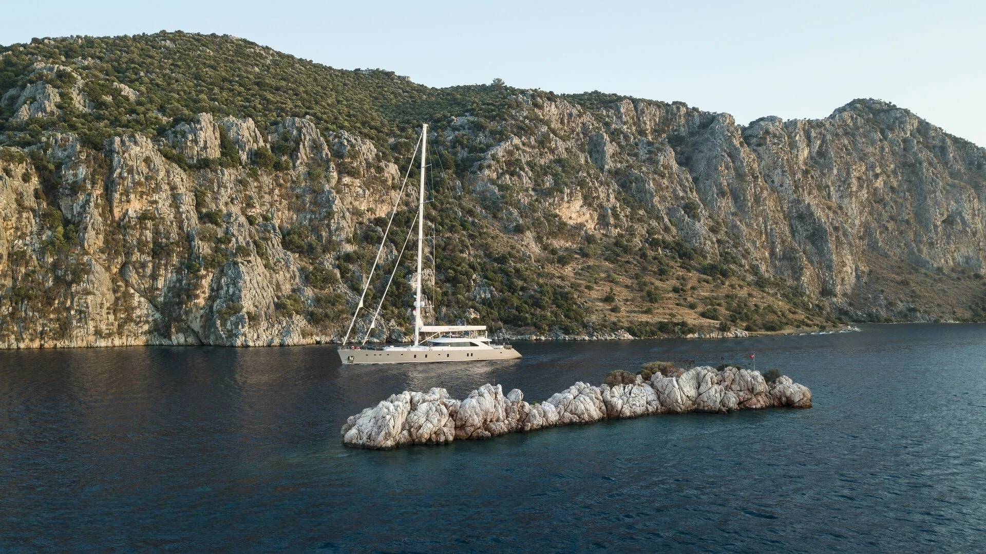 50m motor sailer anchored below cliffs near Bodrum — crewed superyacht charter Turkey AA5019