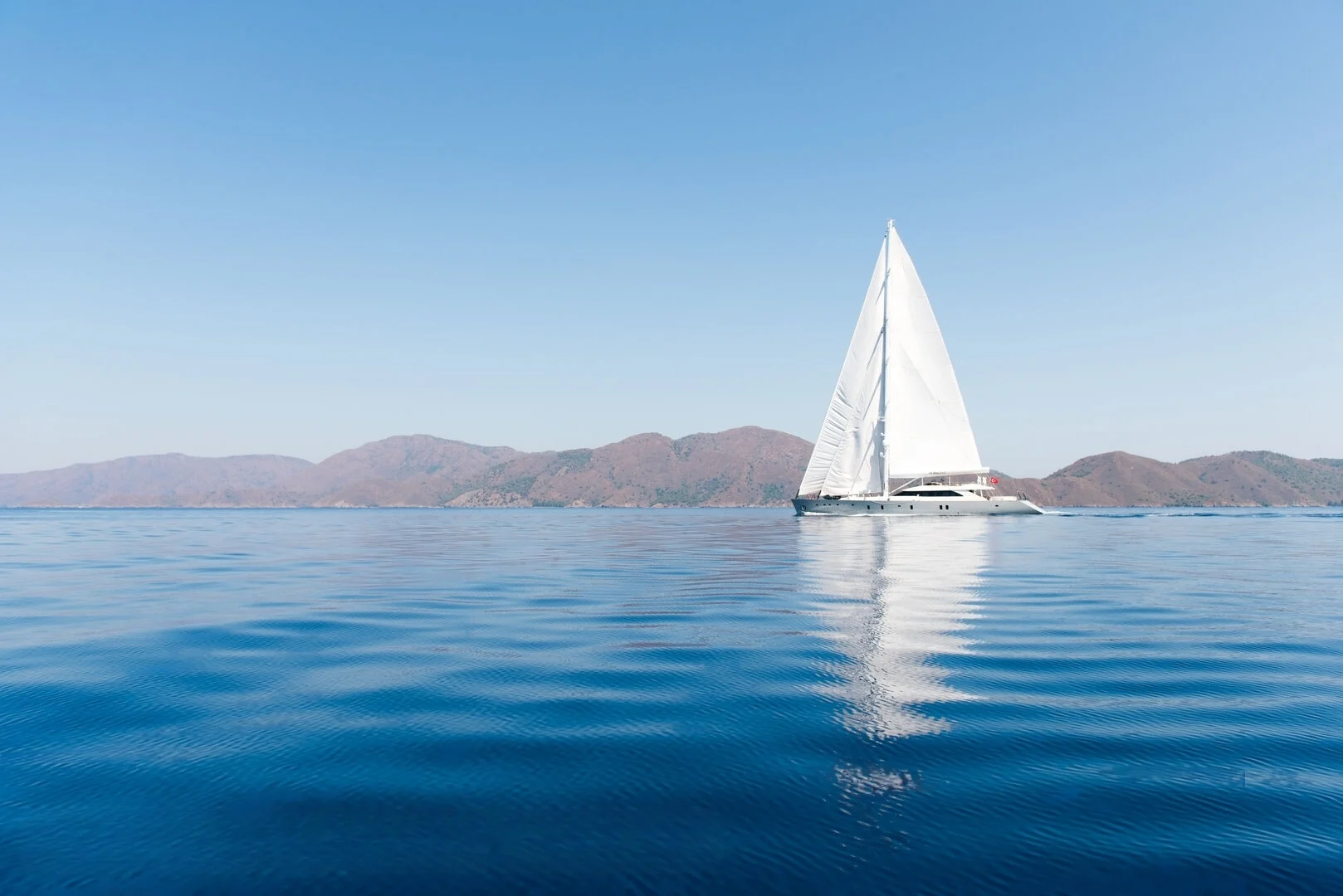 50m motor sailer under sail off the Turkish coast — crewed superyacht charter AA5019
