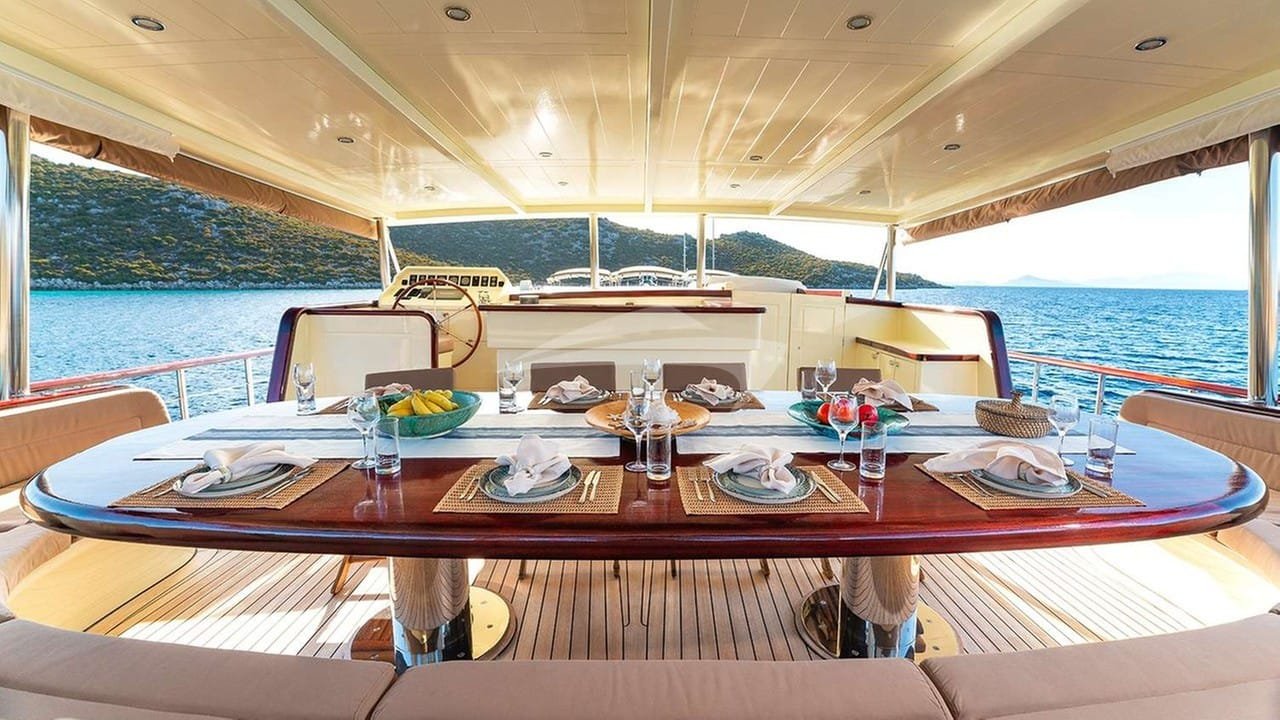Aft deck table set for lunch aboard a crewed motor yacht charter in Gocek, teak decking and a curved settee