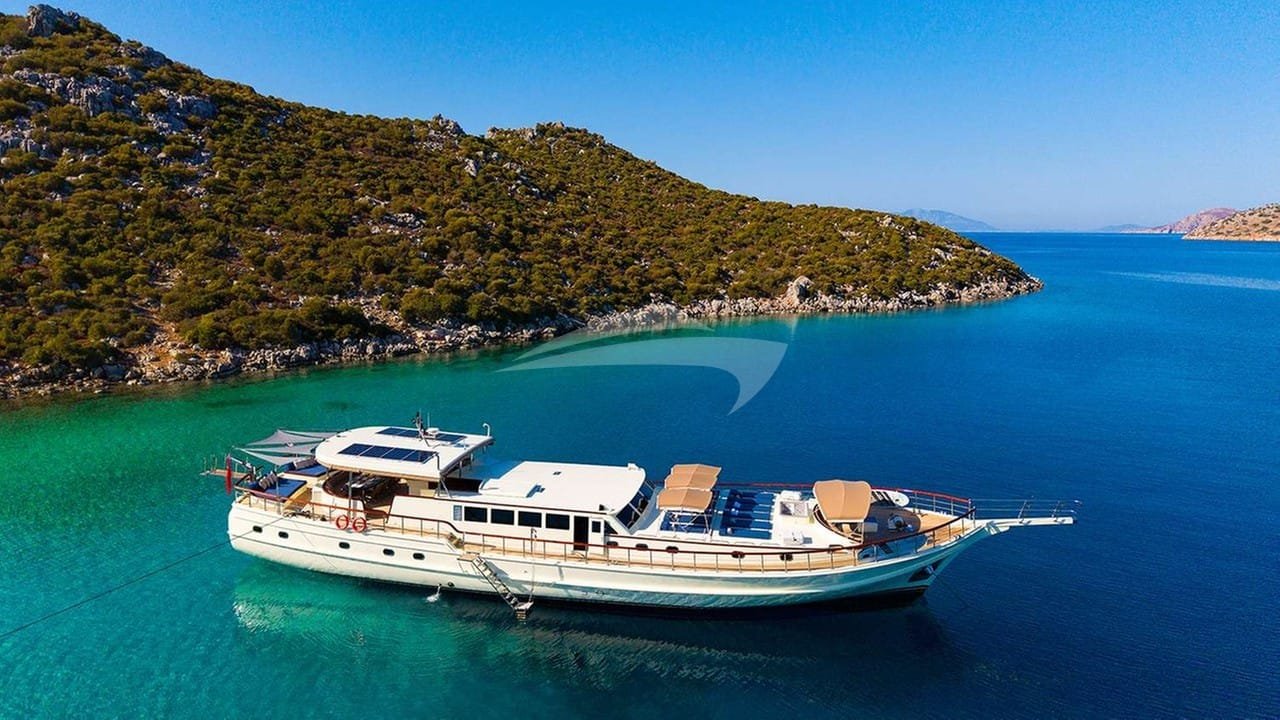Crewed motor yacht charter Gocek lying at anchor off a pine-covered island in the Gulf of Fethiye