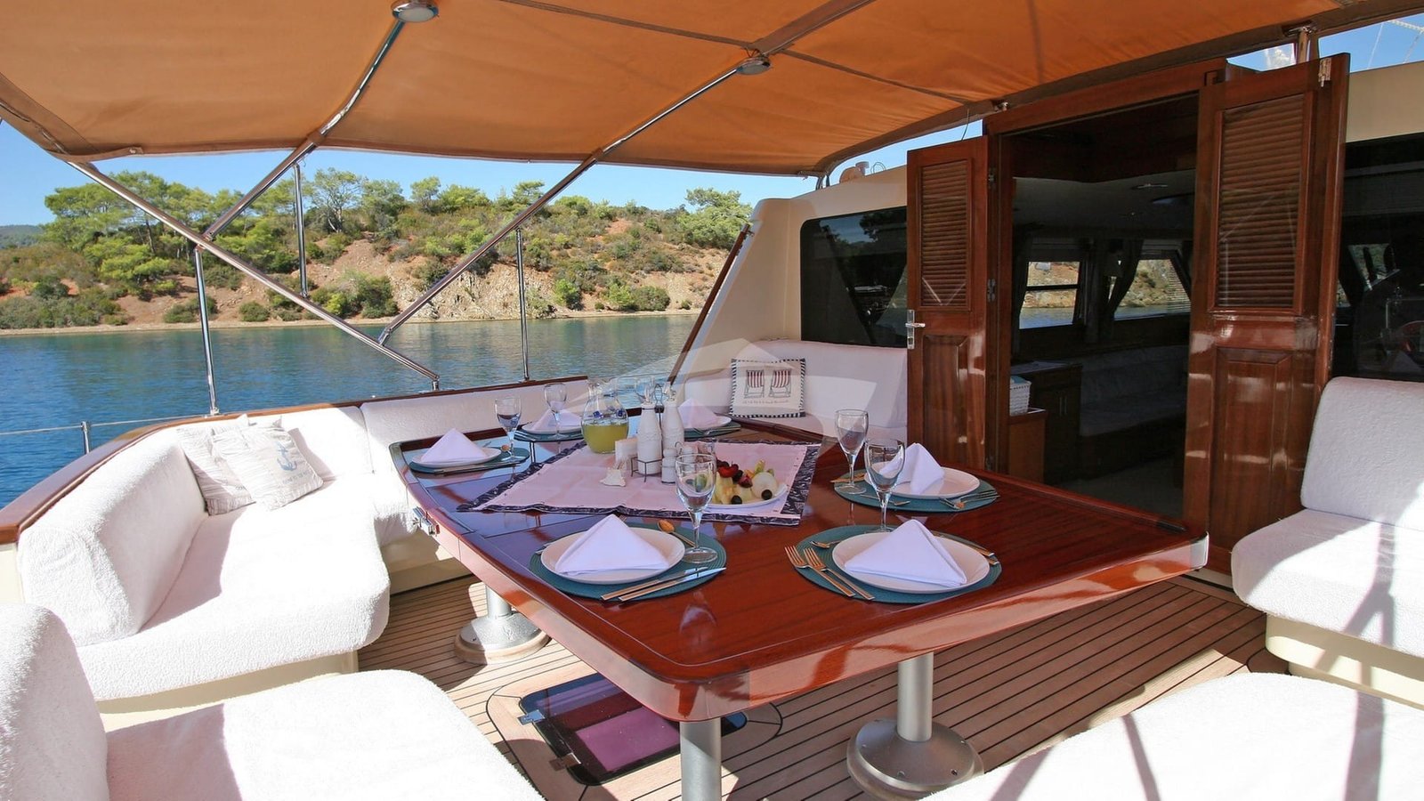 Aft deck dining table laid under the awning of a crewed sailing yacht in Bodrum