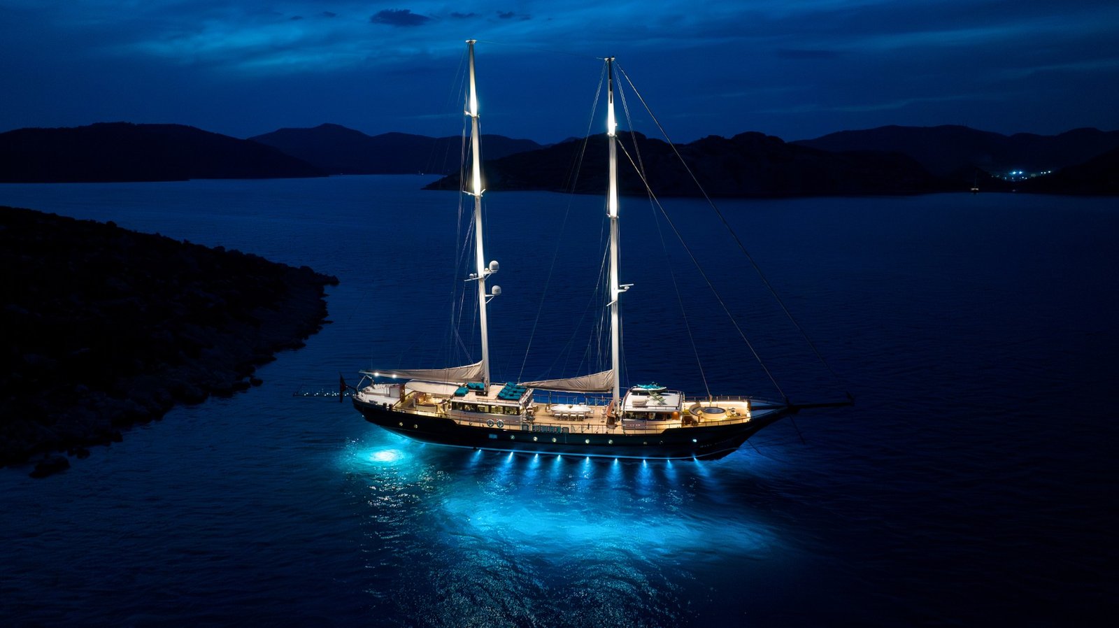 Night aerial of a 43m crewed motor sailer anchored off a Turkish cove — MN4308
