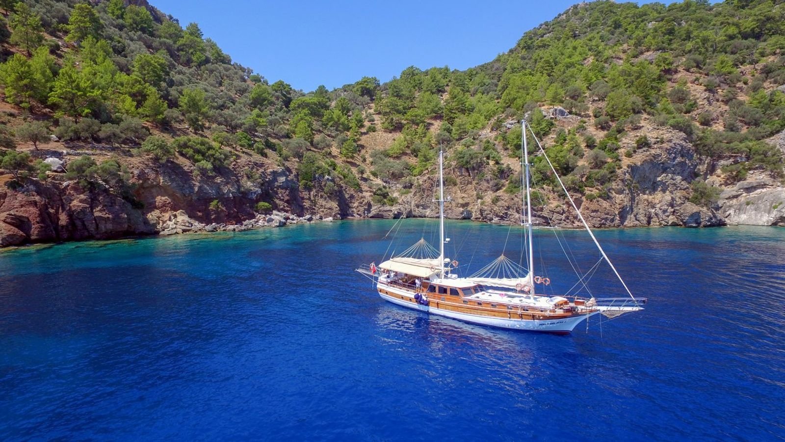 A gulet charter Marmaris vessel lying to a stern line in a rocky cove