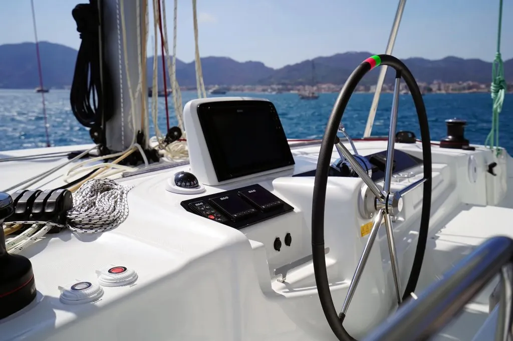 Helm controls of a Lagoon 46 charter catamaran, wheel, plotter and halyard winches within reach