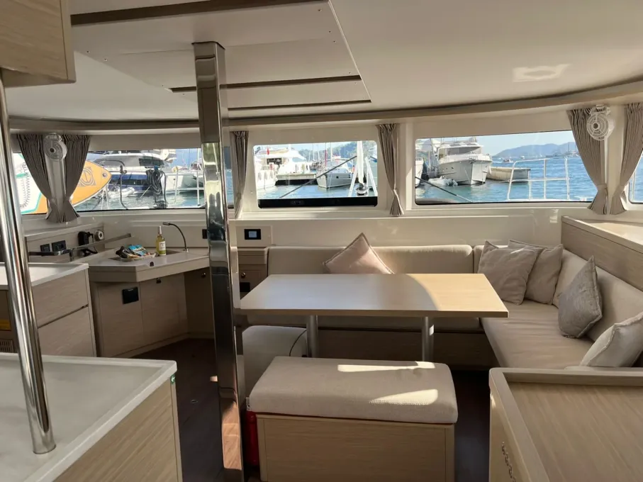 Saloon dining table of the Lagoon 46 charter catamaran with panoramic glazing across the front