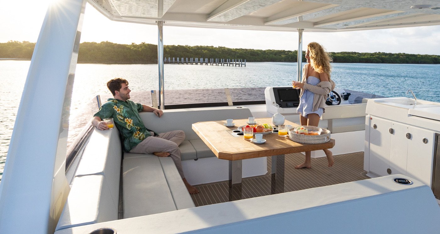 Shaded aft cockpit of a Leopard 46 Powercat charter yacht set for lunch with a teak table and L-shaped settee