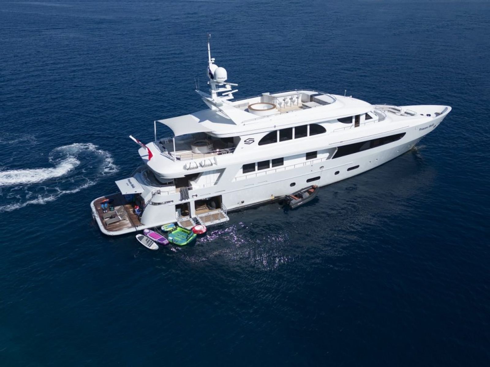 Aerial view of a 42m luxury motor yacht with the beach club and water toys deployed