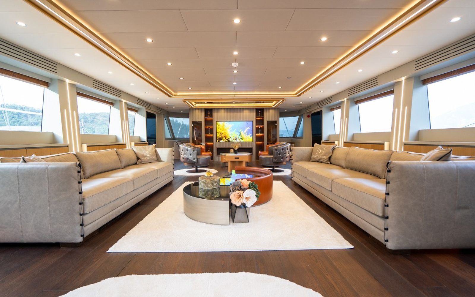 Main saloon with cream sofas and panoramic windows on a luxury sailing yacht charter