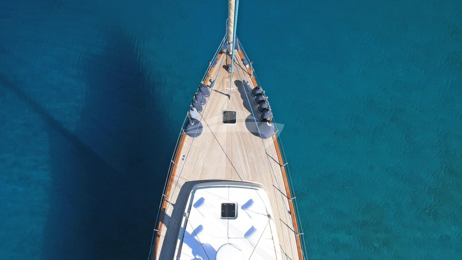 Aerial view over the teak foredeck of a crewed sailing yacht at anchor near Bodrum