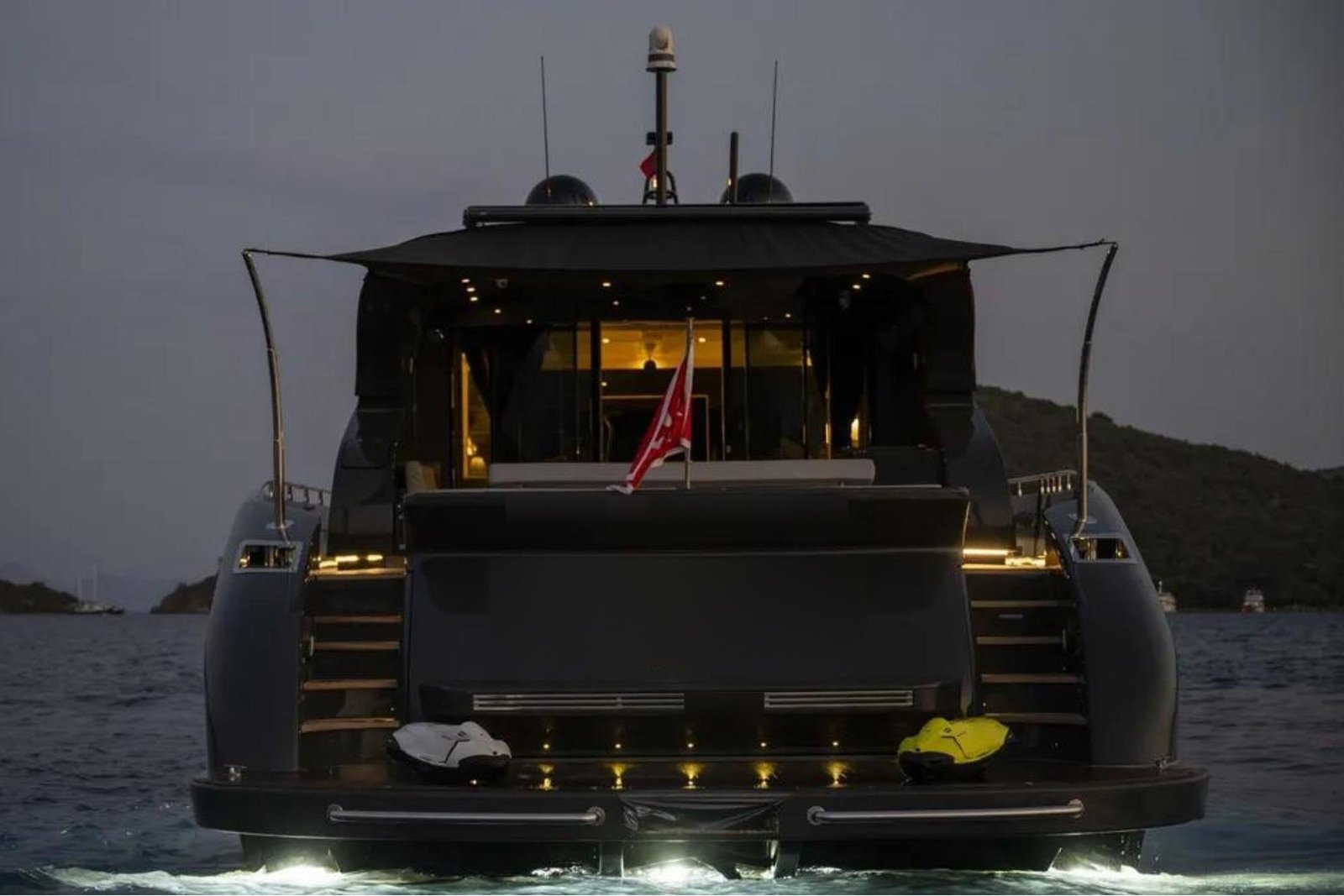 Stern, bathing platform and lit aft deck of an AB Yachts 92 charter Göcek at dusk