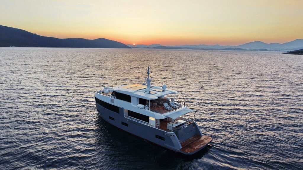 26m Aegean Explorer motor yacht UK2606 cruising at sunset off Sardinia, aerial view, crewed luxury charter Aquinox Yachting
