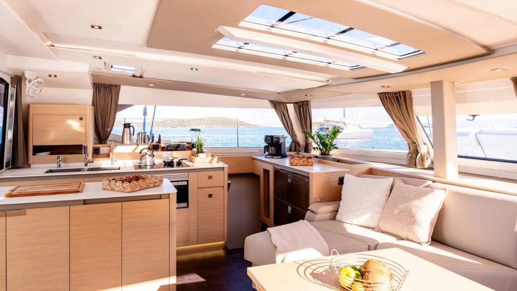 Aura 51 catamaran saloon lounge with sofa, TV and navigation station opening to the cockpit, Rhodes charter AM1604