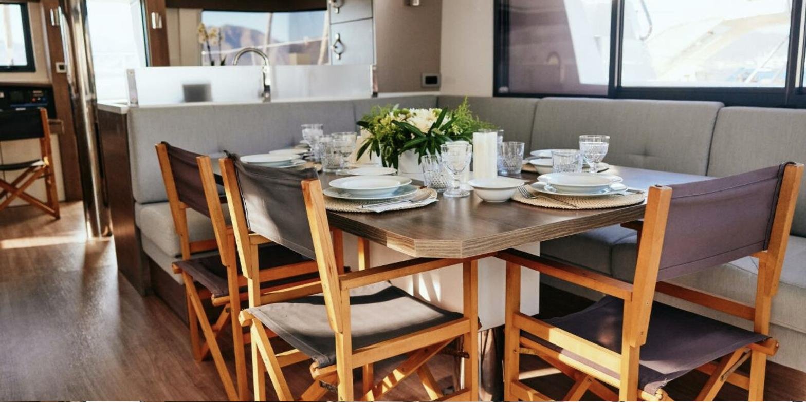 Bali 4.8 charter Marmaris - saloon dining table laid for eight under panoramic windows