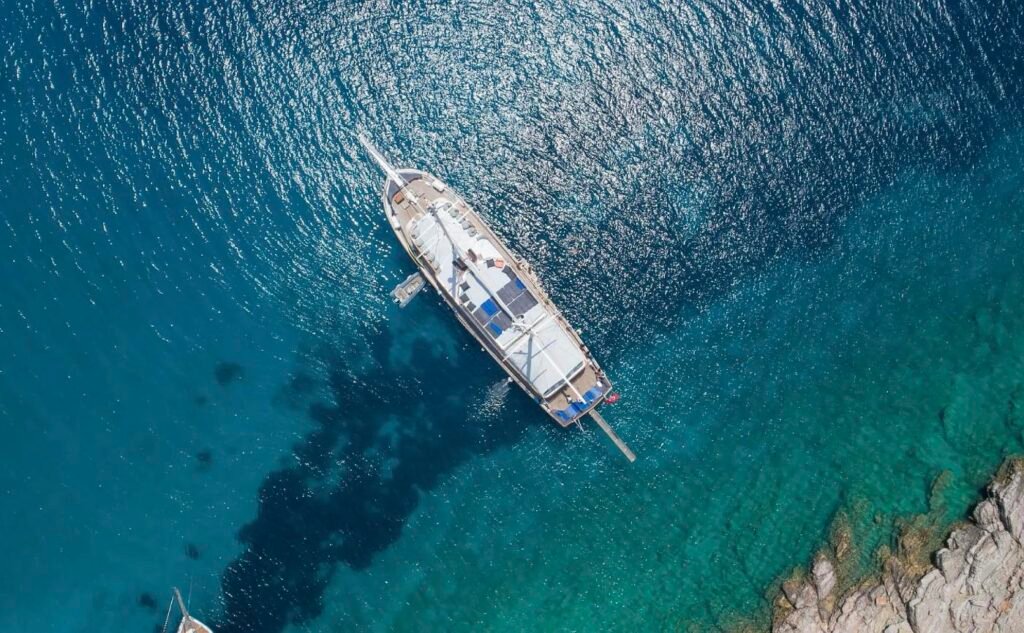 Aerial view of a blue cruise gulet charter Bodrum yacht anchored stern-to the rocks