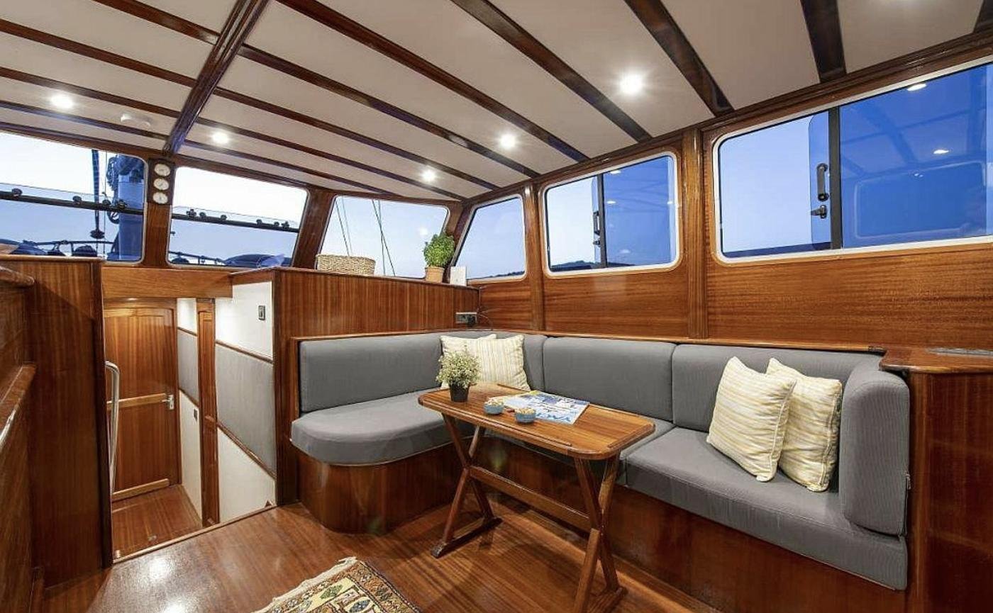 Boutique gulet charter Bodrum - mahogany saloon lit for the evening with soft seating