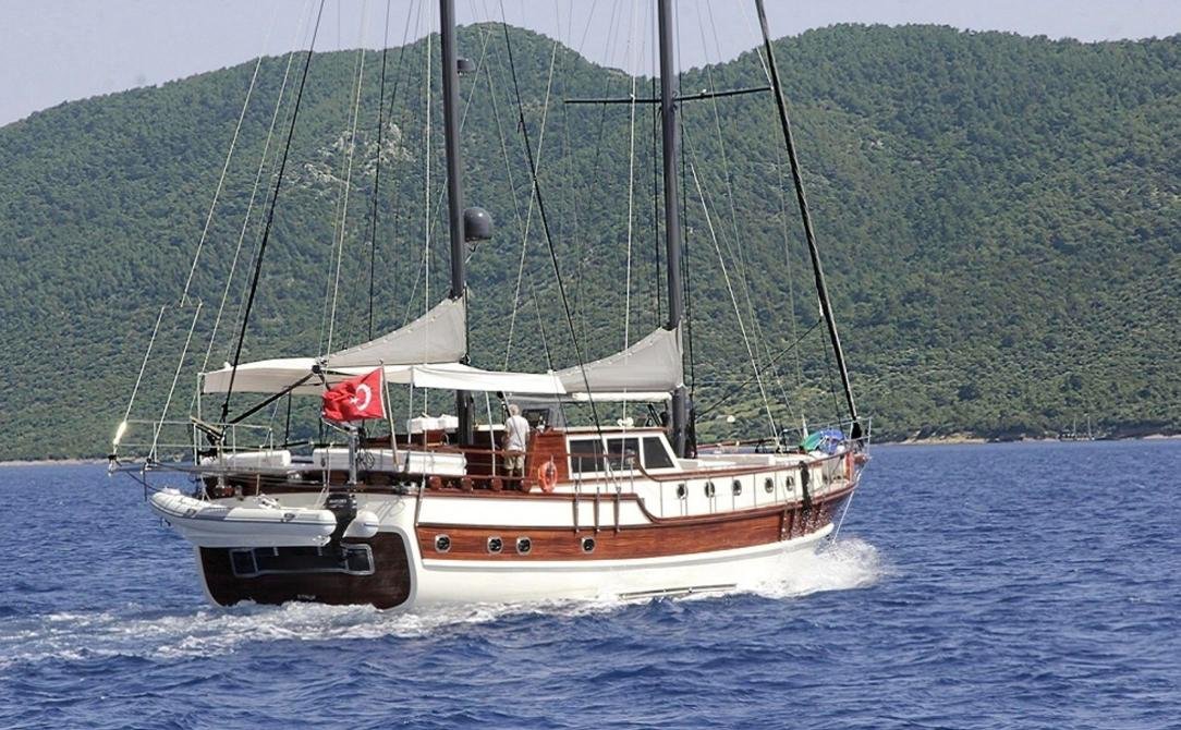 Contemporary gulet charter Bodrum - gulet under way past a green headland