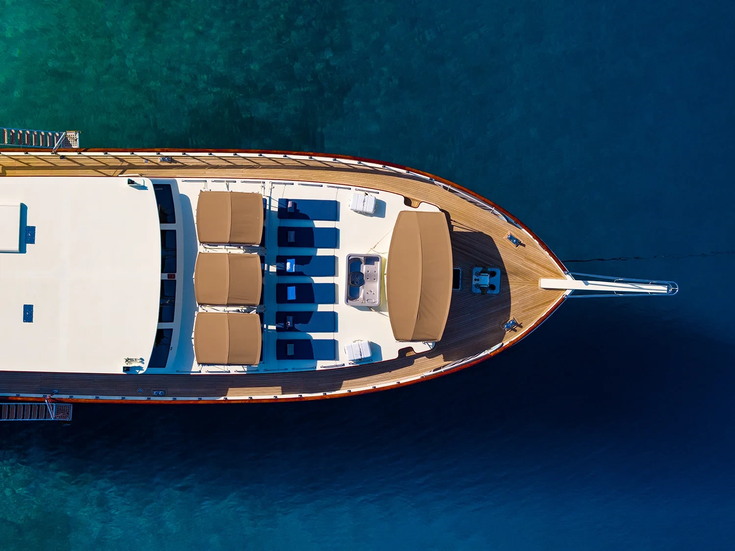 Bird's eye drone view straight down onto the bow deck of a crewed motor yacht charter in Gocek, jacuzzi and sunbeds visible