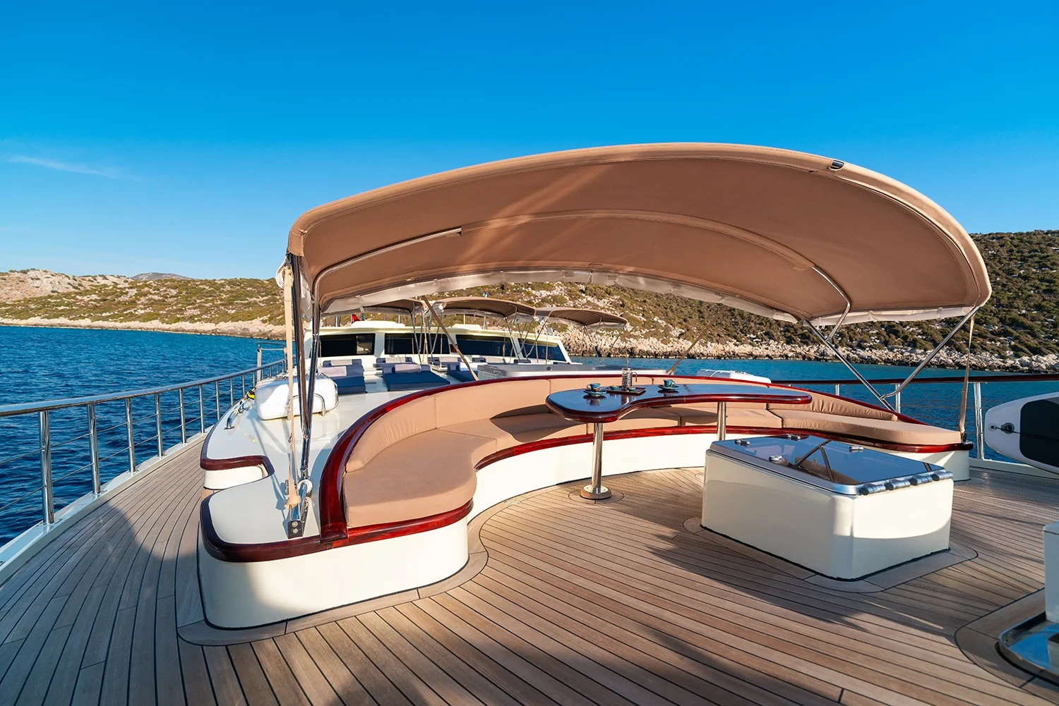 Flybridge lounge and jacuzzi aboard a crewed motor yacht charter in Gocek, curved seating around a teak table