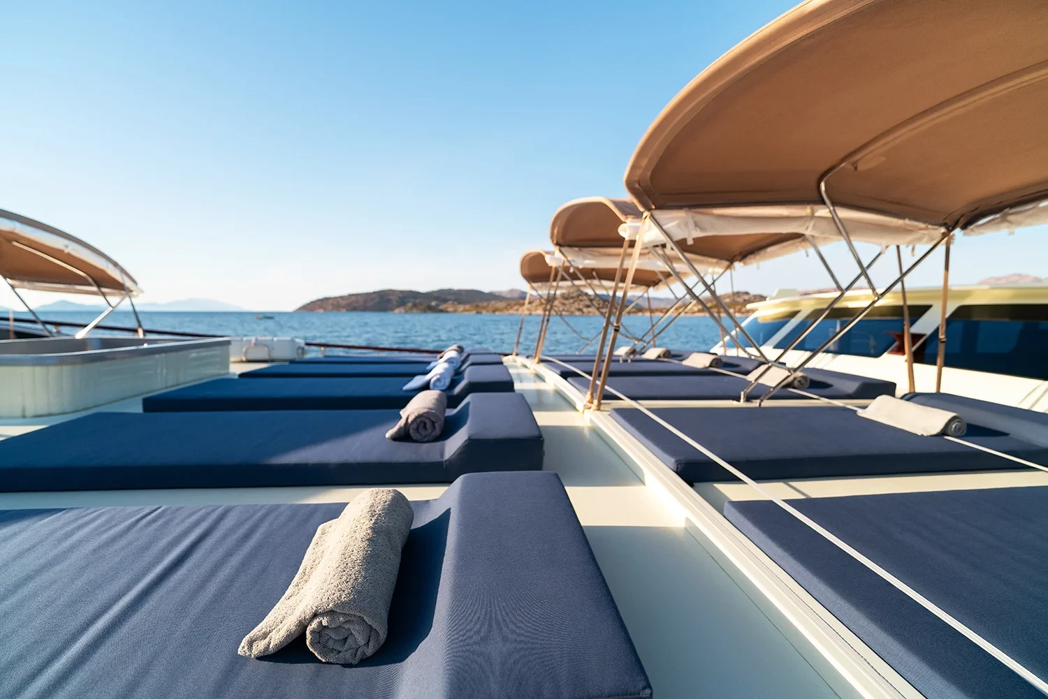 Forward sunbathing area aboard a crewed motor yacht charter in Gocek, rolled towels on loungers under shade awnings