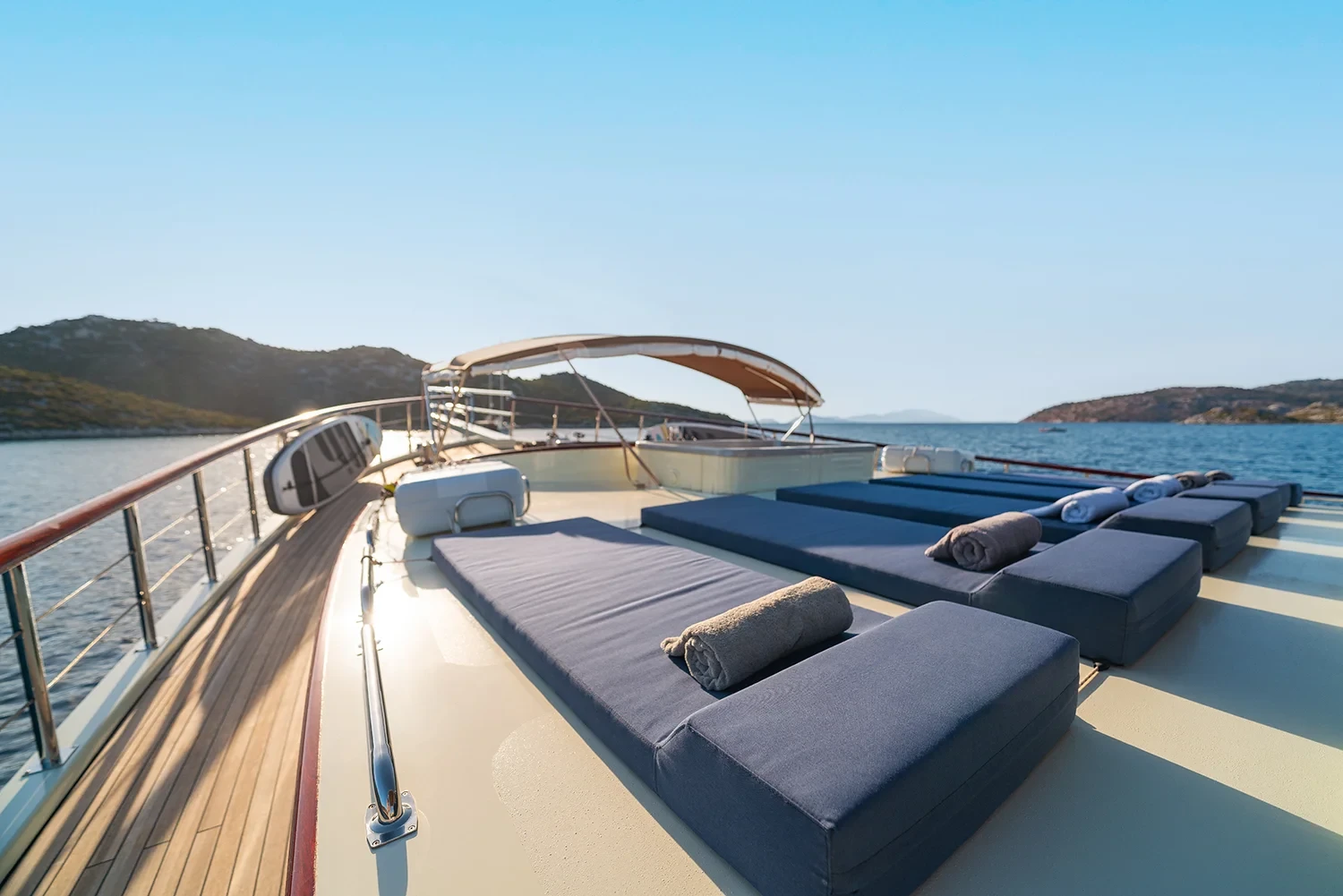 Sundeck loungers aboard a crewed motor yacht charter in Gocek with a paddleboard stowed on the rail
