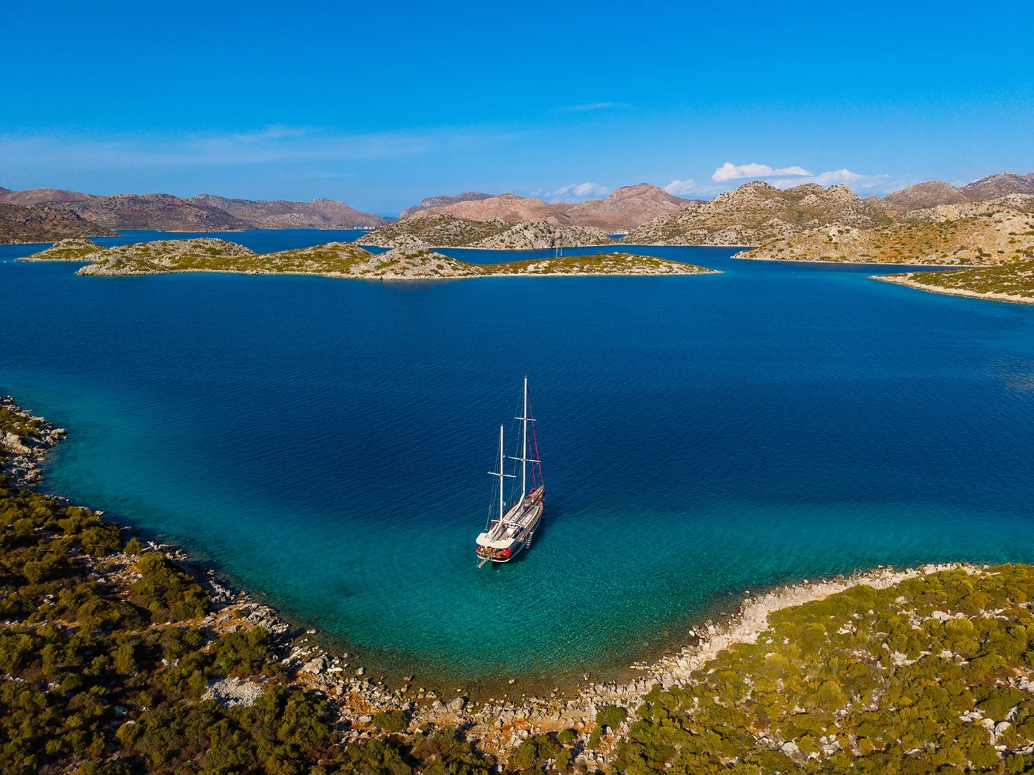 Deluxe motor sailer charter Gocek aerial view anchored in a turquoise cove