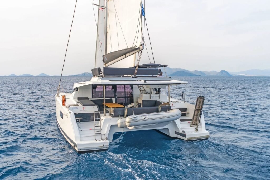 Elba 45 catamaran charter Kos - Elba 45 catamaran aerial view at anchor beneath limestone cliffs in a secluded cove, Kos charter NB1306