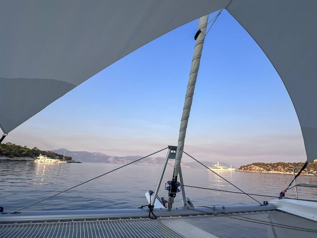 Bir Yunan koyunda akşam yelken altındaki Elba 45 katamaran AL1306'nın baş güvertesi ve trambolini