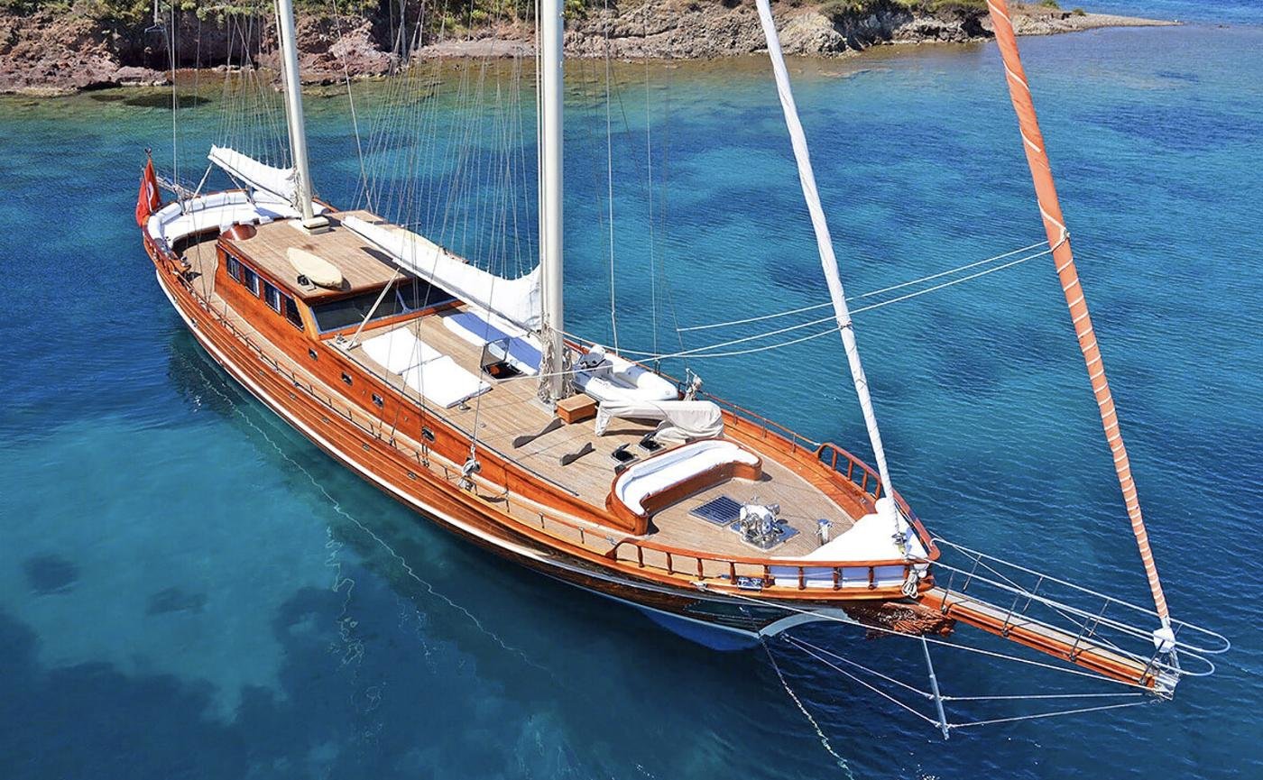 Elegant gulet charter Bodrum - aerial view of a 30m mahogany gulet at anchor in clear water