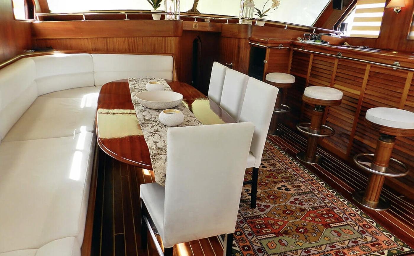 Elegant gulet charter Bodrum - main saloon banquette and polished mahogany dining table