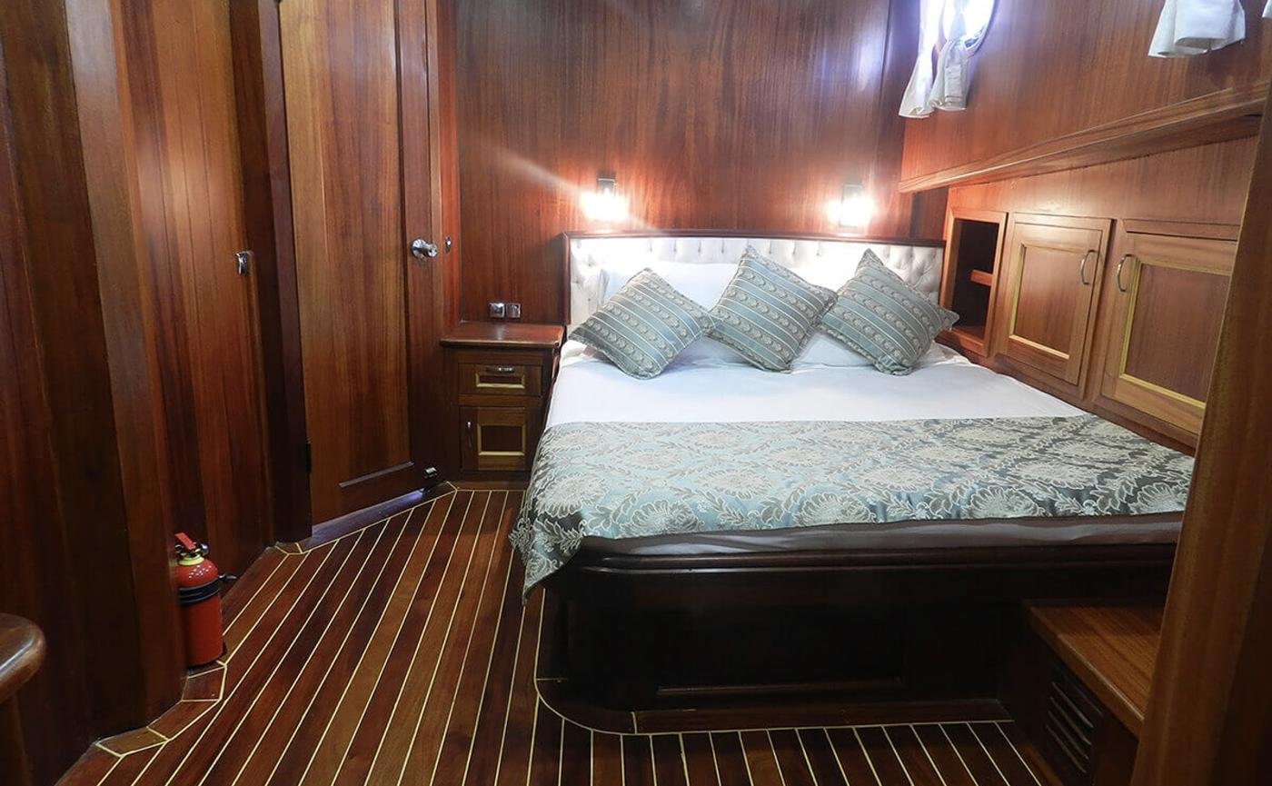 Elegant gulet charter Bodrum - master cabin with buttoned headboard and mahogany panelling