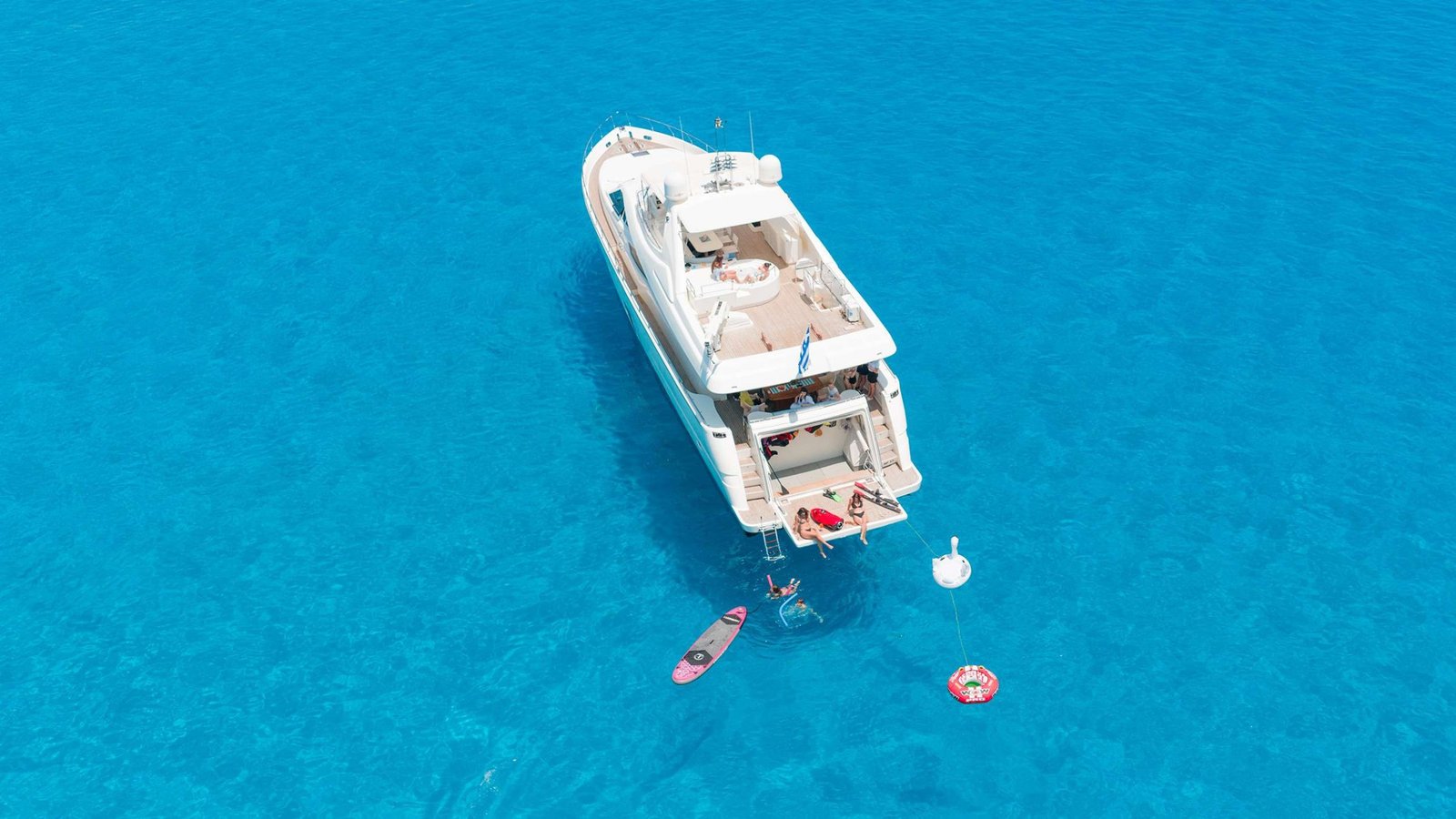 Ferretti 830 Fly charter Rhodes at anchor in turquoise water with guests on the extended swim platform