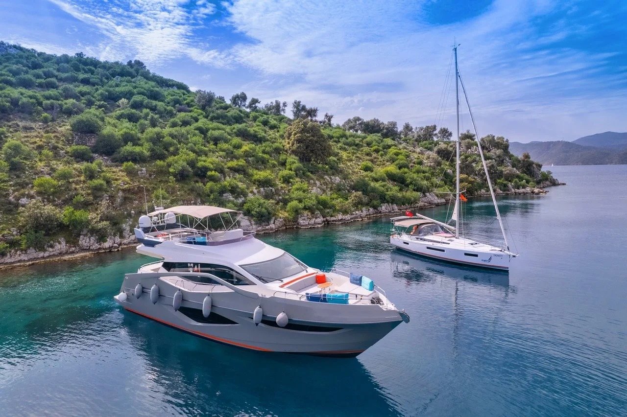 Aerial drone view of a flybridge motor yacht anchored near a Turkish Riviera cove