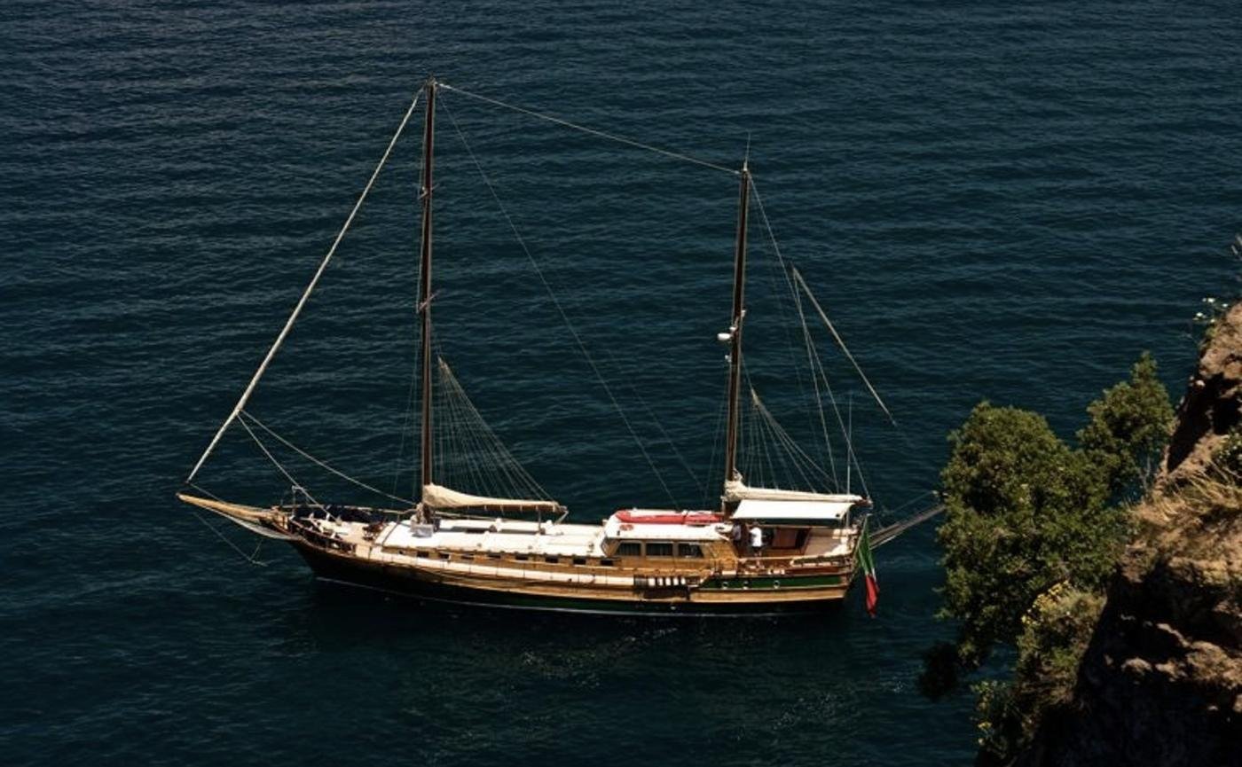 Gulet charter Positano anchored close under an Amalfi Coast cliff