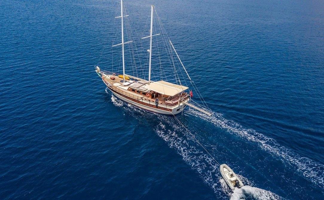 Intimate gulet charter Bodrum - gulet towing her tender across deep blue water