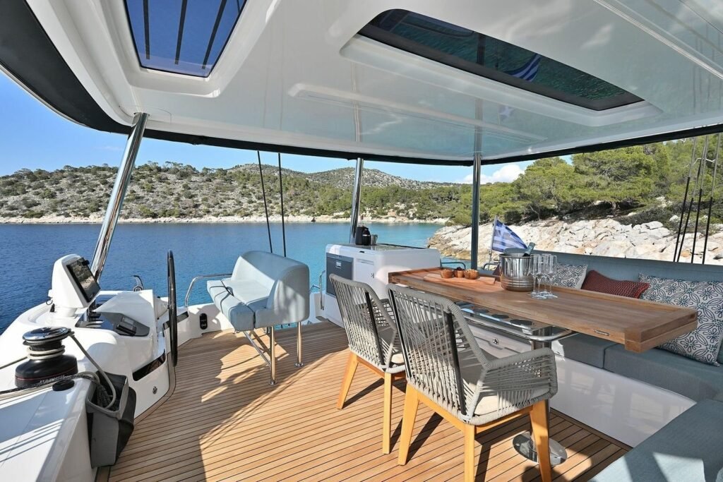 Lagoon 55 catamaran aft cockpit lounge and lowered swim platform with guests swimming in a rocky cove, Kos charter UT1704