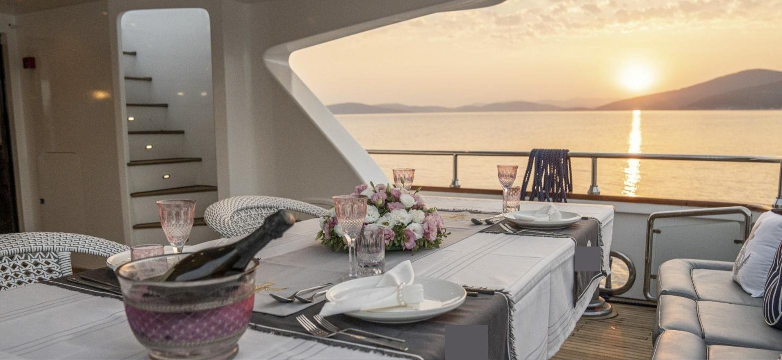 Bodrum'da kiralık Lürssen 144'te gün batımında kıç güvertede yemek