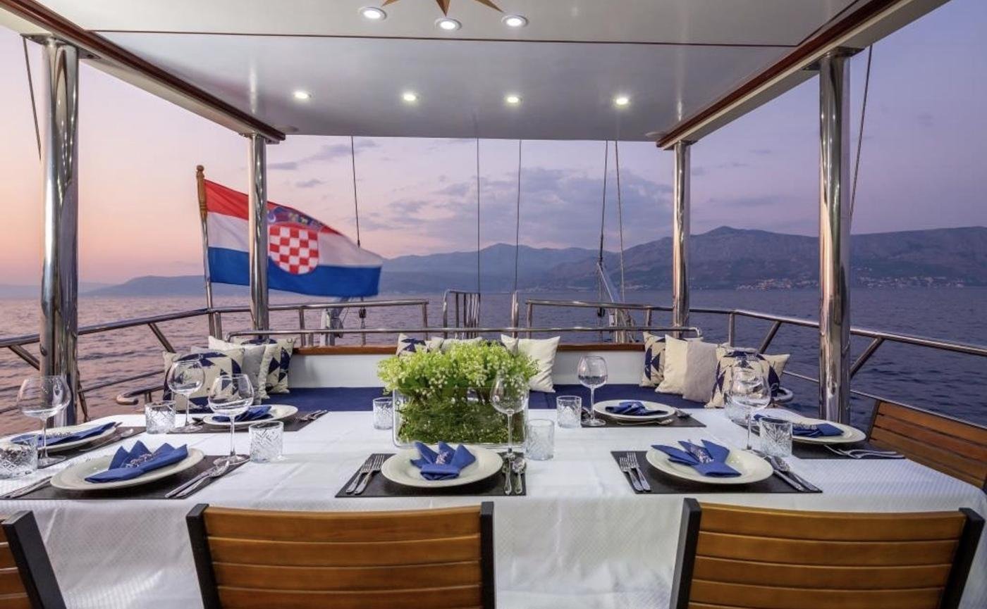 Split lüks kiralık motorsailerda gün batımında kurulmuş kıç güverte yemek masası