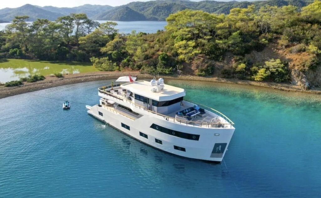 Fethiye lüks trawler kiralama — turkuaz bir koyda demirli 30 metrelik trawlerın havadan görünümü