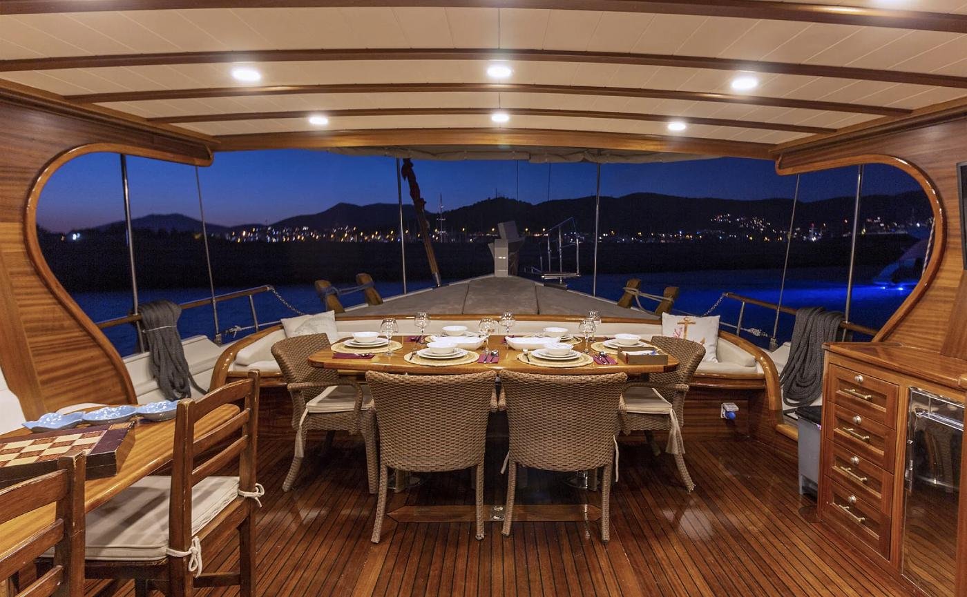 Bodrum motorlu gulet kiralamasında alacakaranlıkta kıç güvertede yemek