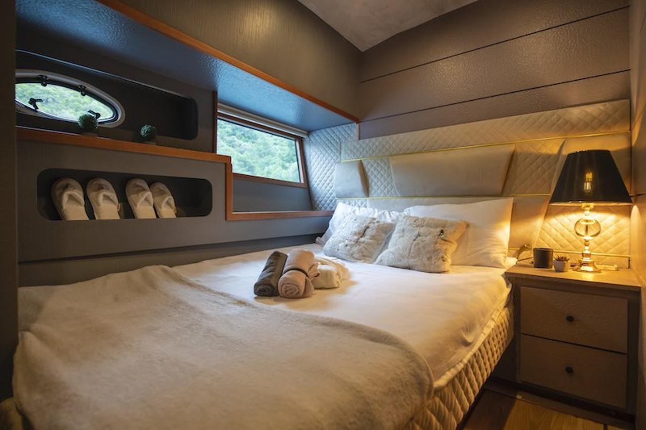 Master cabin headboard, bedside lamp and built-in storage nook aboard a luxury motor yacht