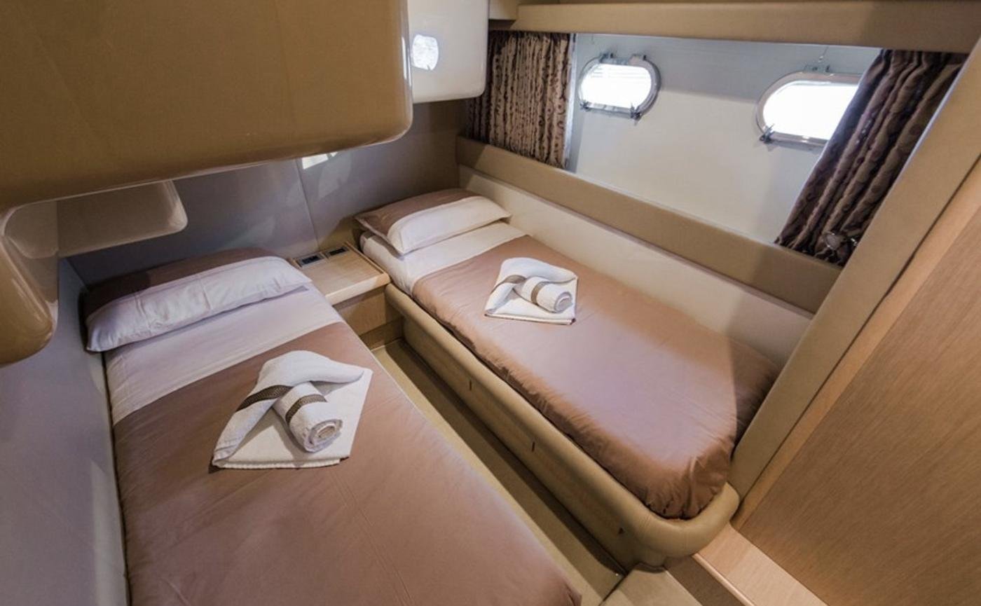 Twin cabin with two single berths and portlights on the Paros motor yacht charter