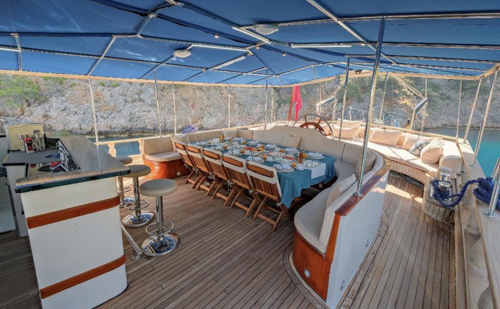 Shaded aft deck dining under a blue awning on a 36m gulet chartered in Fethiye