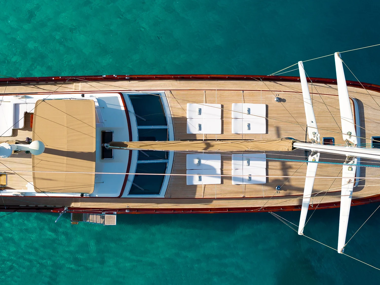 Drone view straight down onto the bow deck of a sailing yacht charter in Bodrum, twin masts and teak deck