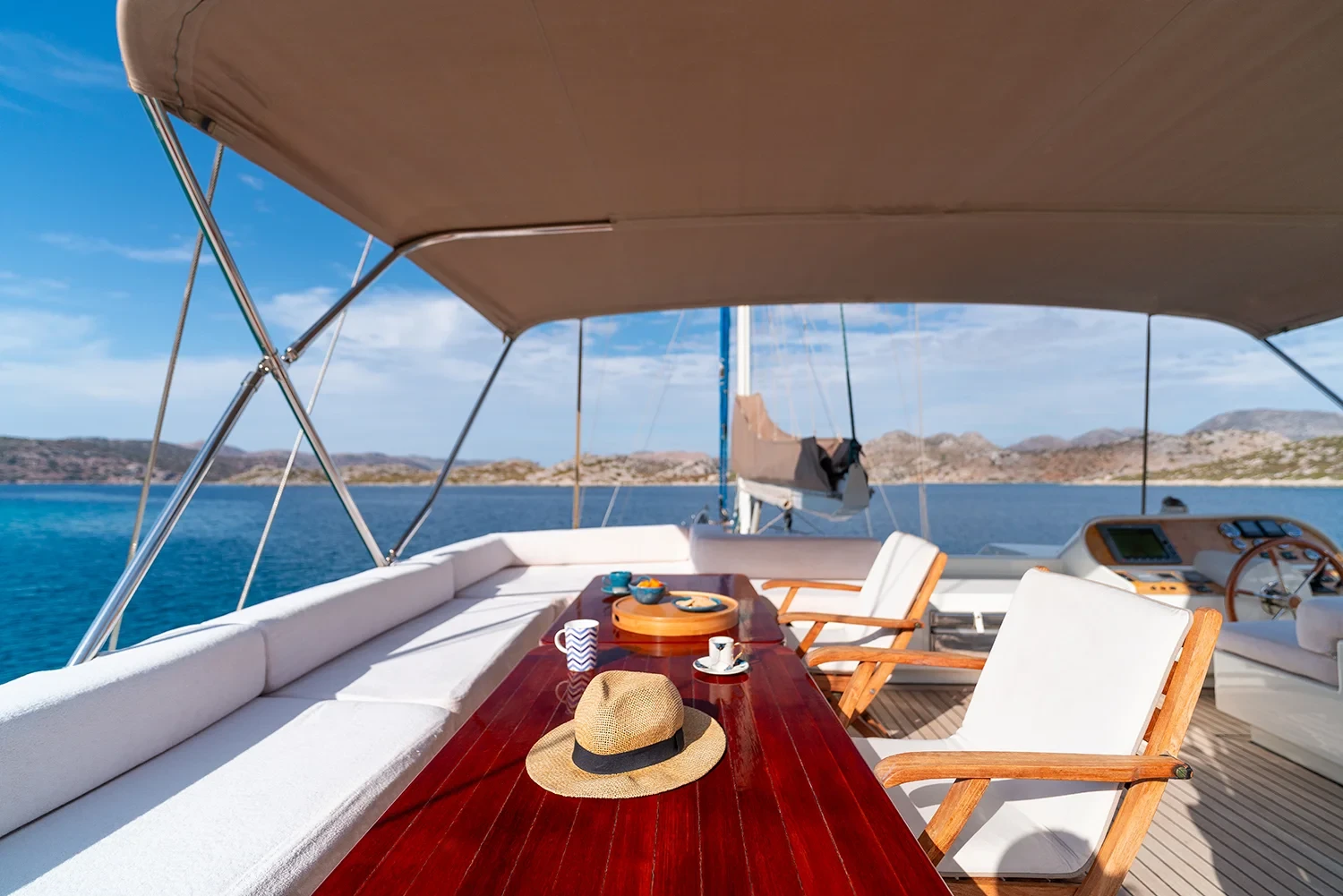 Flybridge alfresco dining table aboard a sailing yacht charter in Bodrum, set for breakfast under the awning