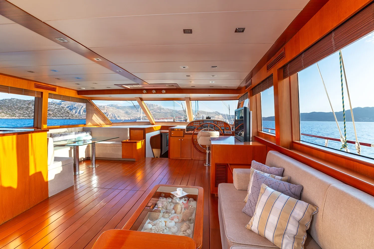 Saloon seating and interior helm of a sailing yacht charter in Bodrum with a glass coffee table