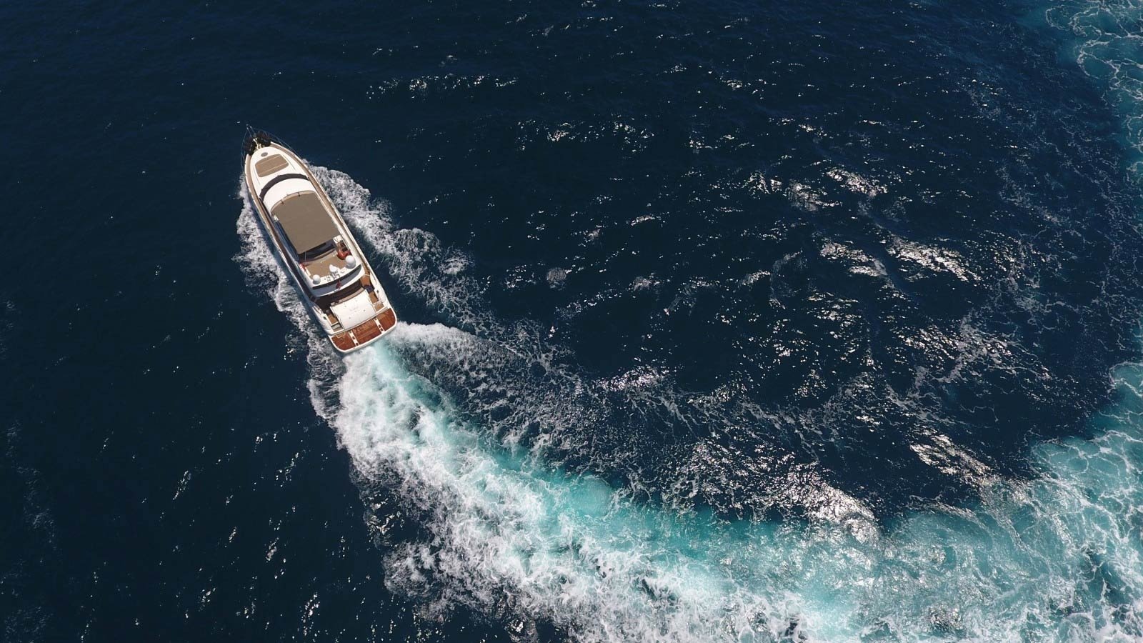 Aerial drone view of a 24m Sunseeker Manhattan 74 motor yacht cruising with a broad wake off Göcek