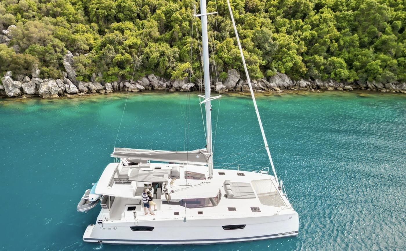 Tanna 47 charter Marmaris - drone view of the catamaran anchored below a pine-covered shore