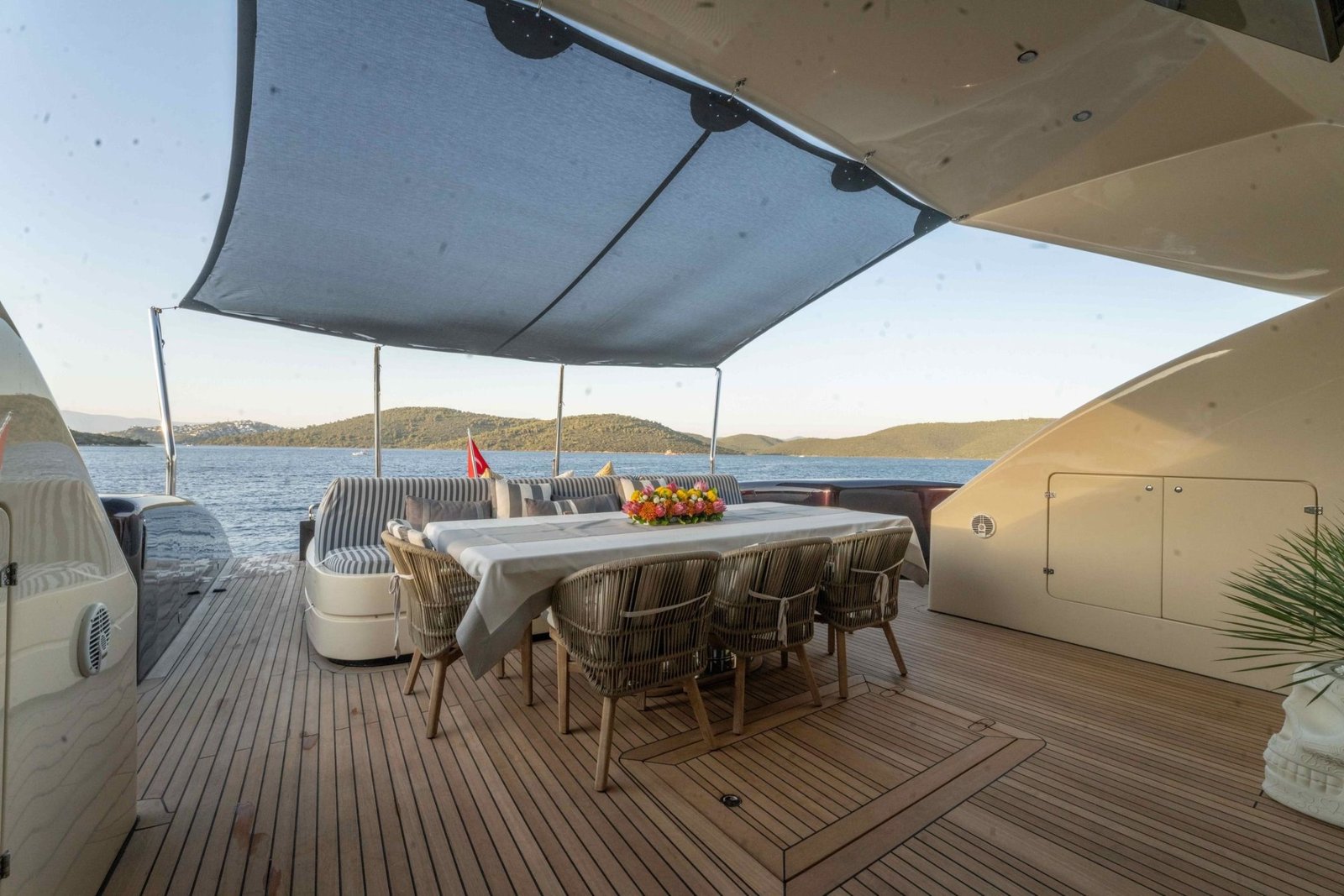 Al-fresco dining table set for eight on the aft deck of a Tecnomar 116 charter Bodrum
